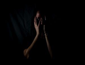 woman holding her face in dark room