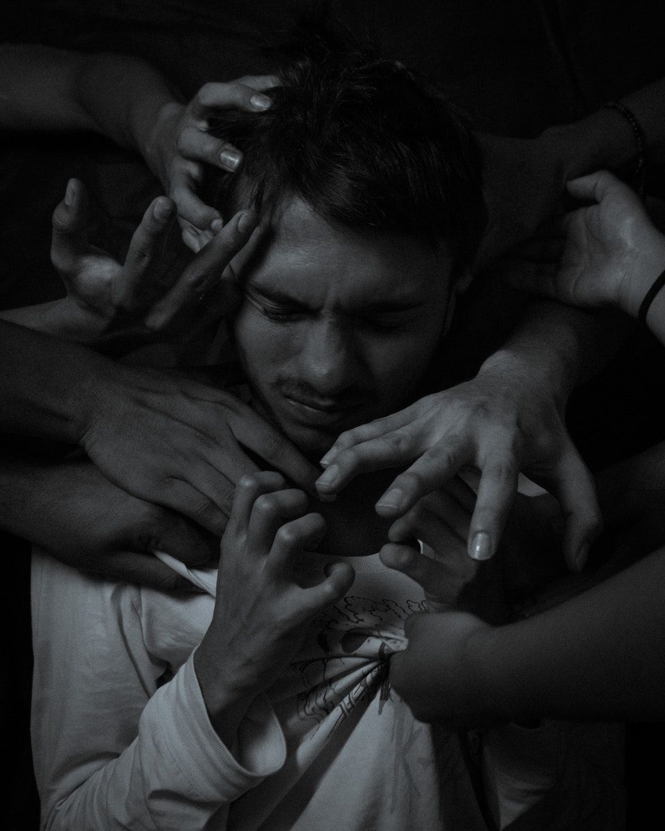 Grayscale Photo of a Man Surrounded by Hands